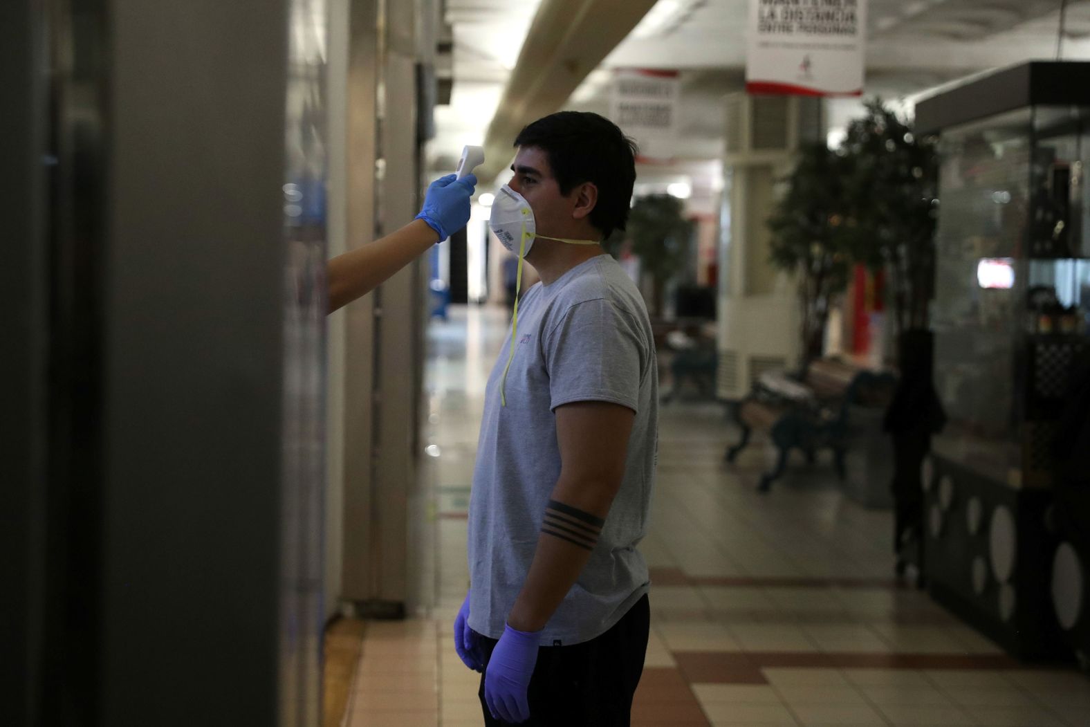 A worker checks a person's temperature as they get ready to reopen a commercial center in Santiago, Chile, on April 29.