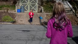 Friends and neighbors, Norah and Elizabeth, talk about their weekends from opposite sides of the road as they maintain social distance in a neighborhood in Syracuse, New York, April 5, 2020, amid a coronavirus disease outbreak.