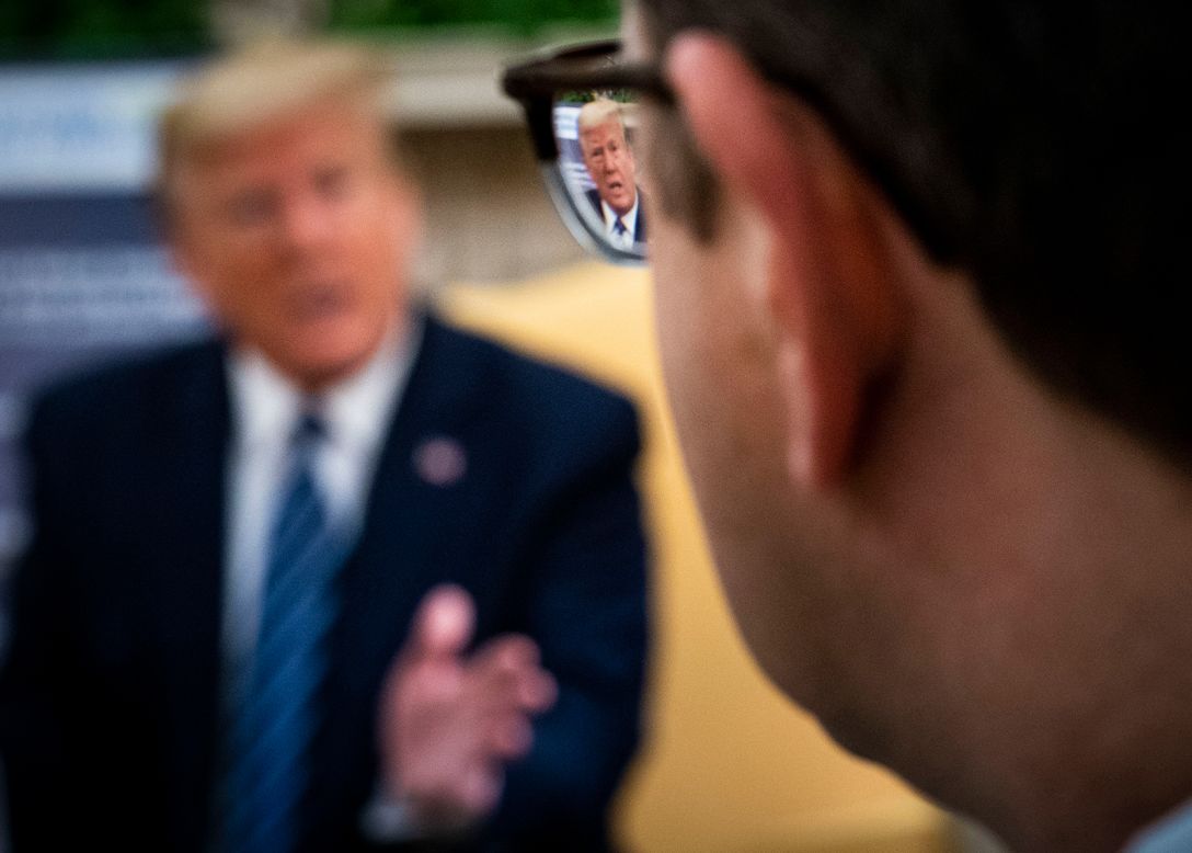 US President Donald Trump is reflected in a pair of glasses as he answers questions in the White House Oval Office on Thursday, April 30. Trump was meeting with New Jersey Gov. Phil Murphy. New Jersey, like many states, is seeking federal assistance because of the coronavirus pandemic.