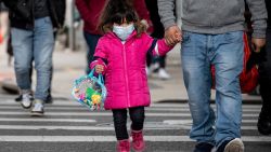 A girl, wearing a mask, walks down a street in the Corona neighborhood of Queens on April 14, 2020 in New York City. - New York will start making tens of thousands of coronavirus test kits a week, its mayor announced Tuesday, as the city looks to boost testing capacity with a view to ending its shutdown. (Photo by Johannes EISELE / AFP) (Photo by JOHANNES EISELE/AFP via Getty Images)