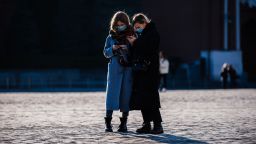 Two women wearing protective face masks due to fears of the coronavirus disease (COVID-19) use their smartphones while standing on Red Square in downtown Moscow on March 17, 2020. (Photo by Dimitar DILKOFF / AFP) (Photo by DIMITAR DILKOFF/AFP via Getty Images)