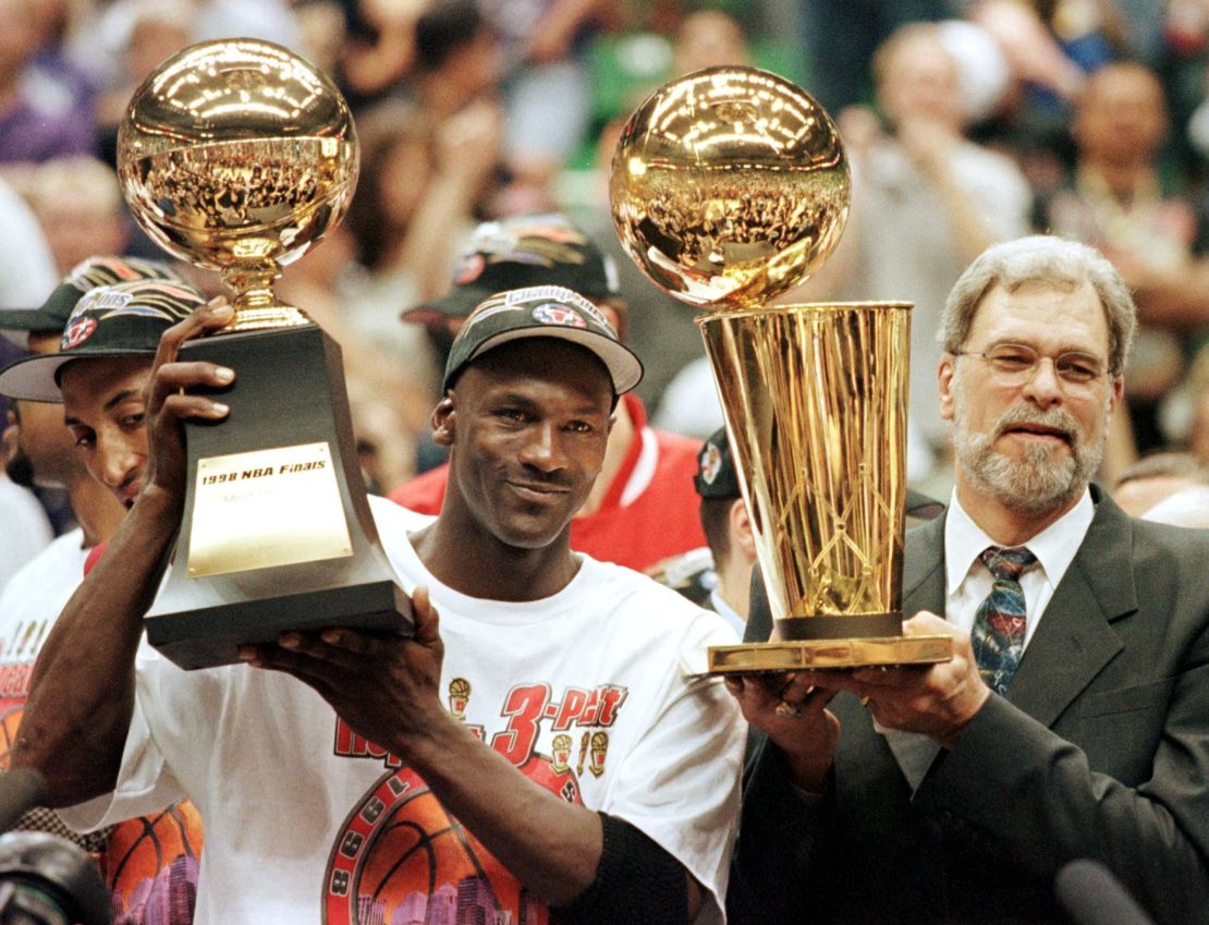 Jordan, seen here with Phil Jackson, raises his NBA Finals MVP trophy.