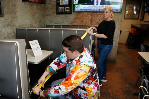 Leslie Wilson helps her son, JP, tape off booths at Falcone's Pizzeria in Oklahoma City on April 30. Restaurants in Oklahoma City were being allowed to reopen, and Falcone's Pizzeria closed some booths to allow for social distancing.