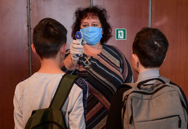 A headmistress screens students' temperatures April 16 at the entrance to a school in the Russian village of Nezhino.