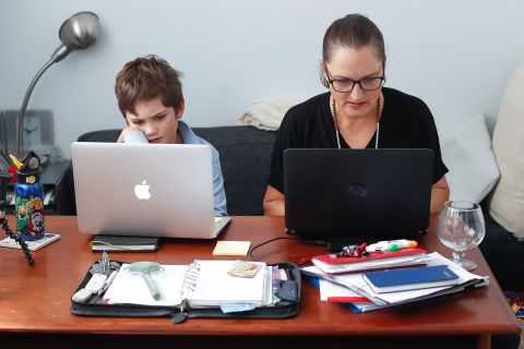 Phoenix Crawford does schoolwork while his mother, Donna Eddy, works from home in Sydney on April 9. Many parents are balancing their own jobs as well as the role of a homeschool teacher for their child.