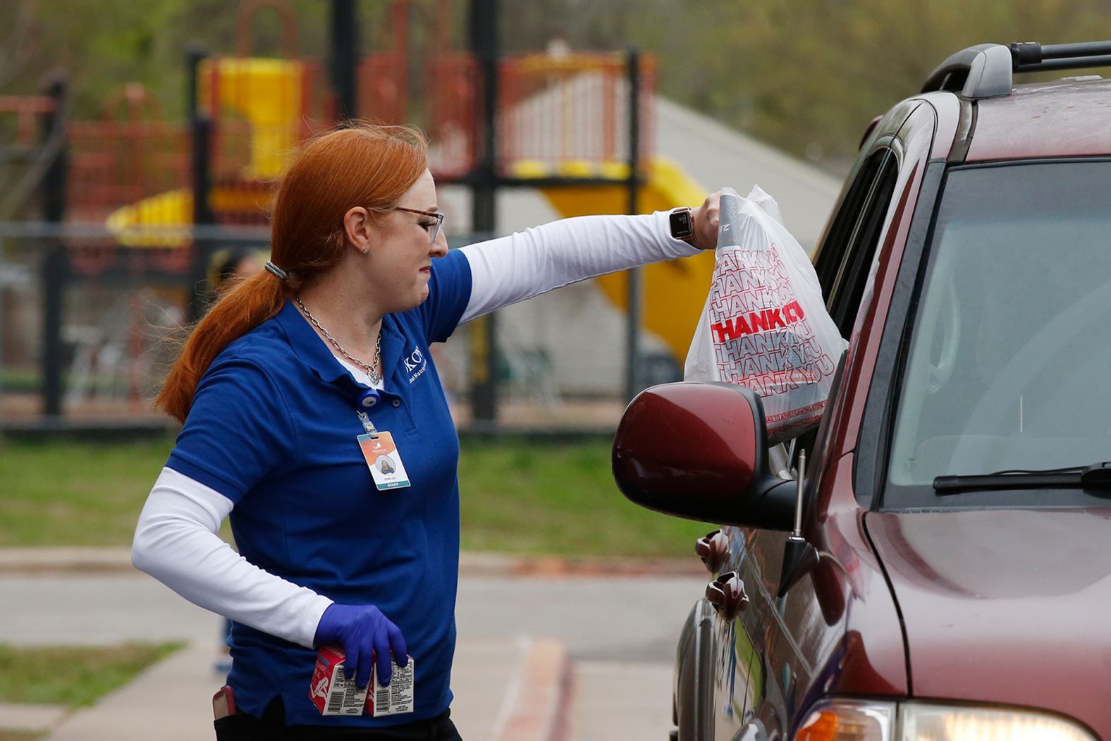 Shonia Hall, director of the Oklahoma City Public Schools nutrition service, hands a bag lunch through a car window at Rockwood Elementary School on March 24. Many students rely on food services from the district. In order to fill that need, some schools have began distributing food for low-income families.