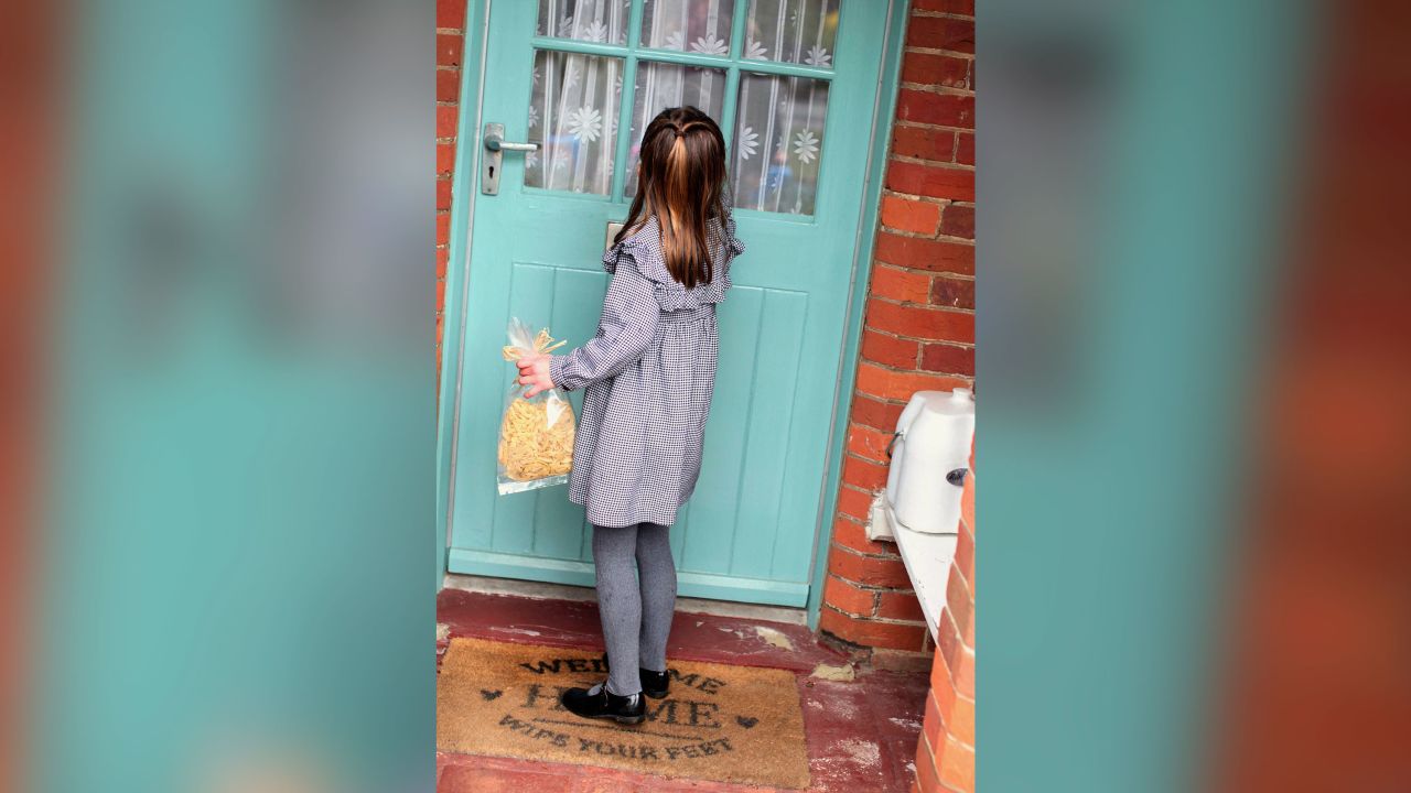 Princess Charlotte approaches a door with a bag of pasta. 