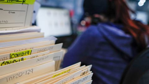 Folders containing information on those who died from Covid-19 are stacked while employee Gina Hansen works at Daniel J. Schaefer Funeral Home in Brooklyn.