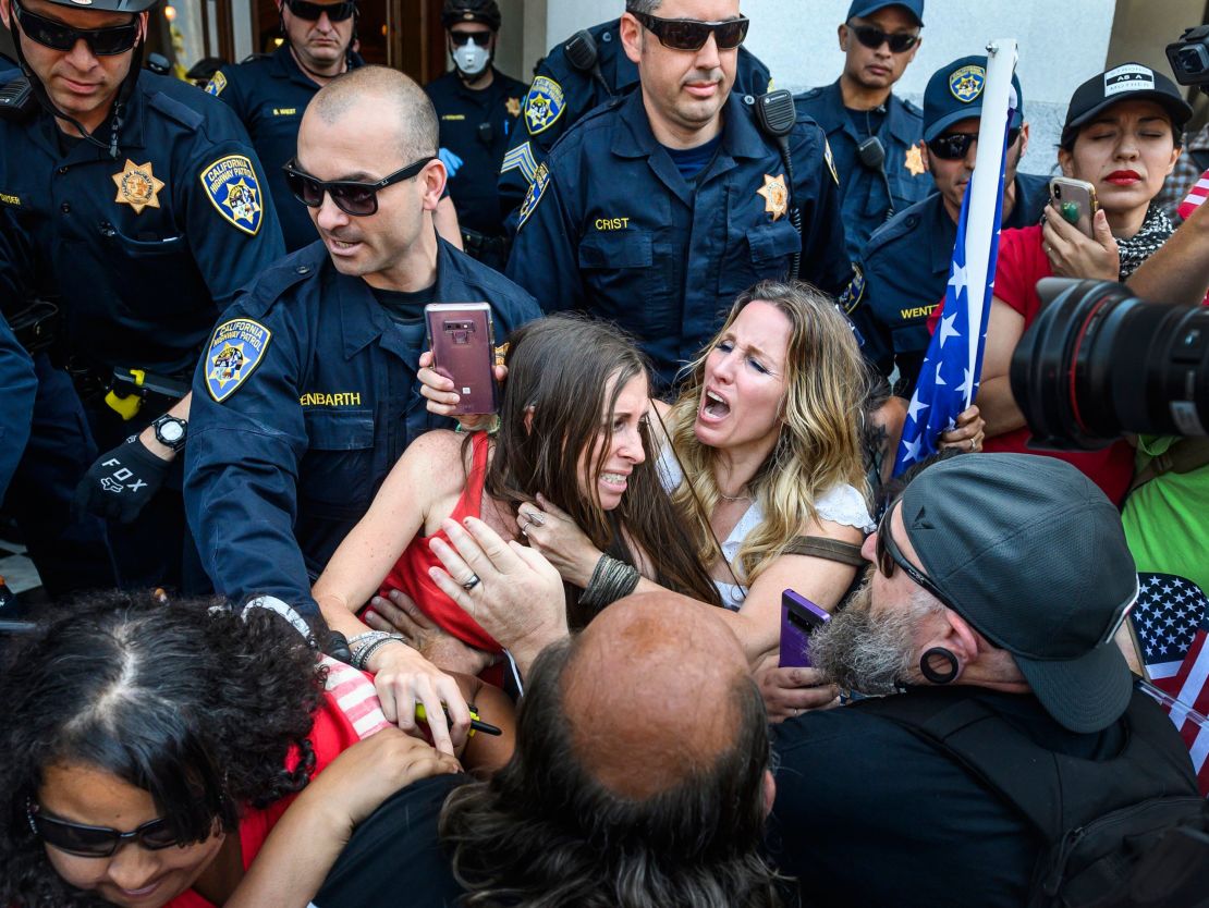 Heidi Munoz Gleisner, center left, is removed from a protest against California's stay-at-home order.