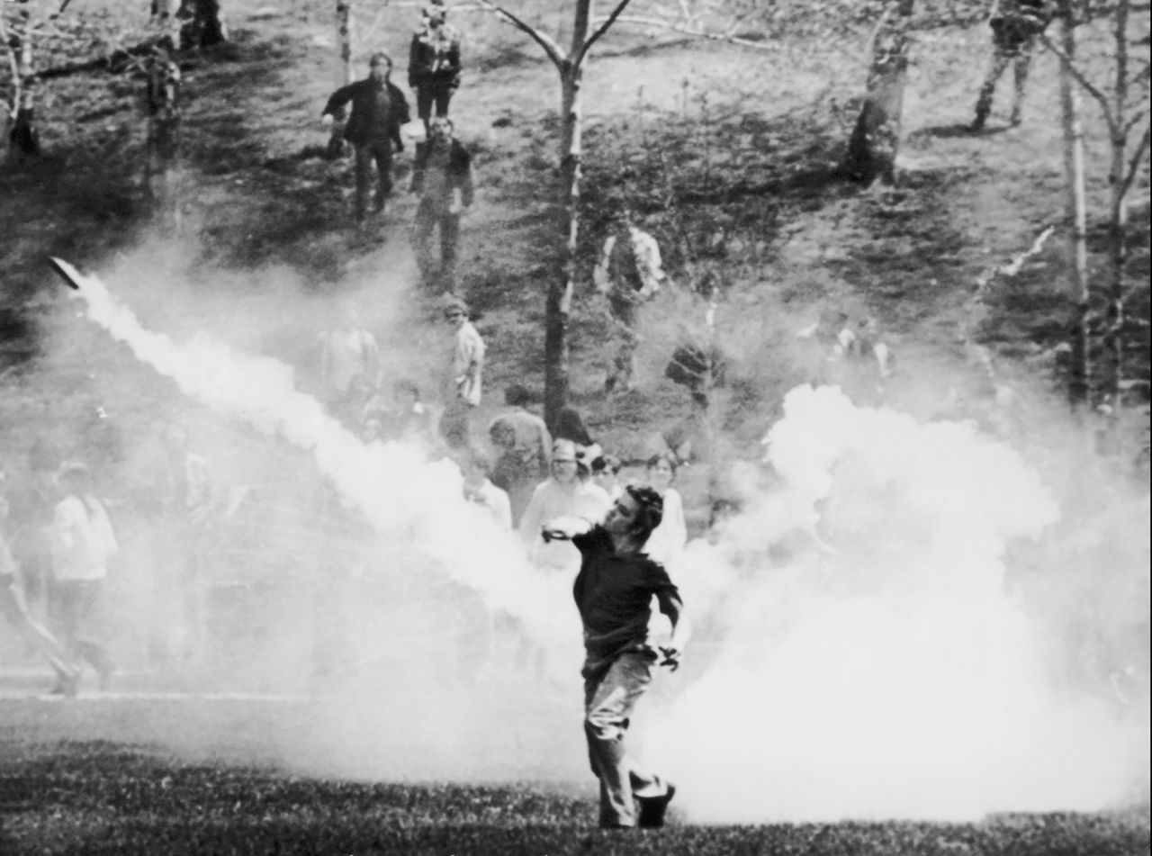 A student throws a tear-gas canister back at guardsmen during clashes on May 4, 1970. After several standoffs, the troops headed back up a hill in the direction of the ROTC building. As they reached the top, they turned toward the demonstrators and opened fire.