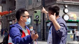People wearing face masks make livestreaming on Qianmen Street on April 25, 2020 in Beijing, China.