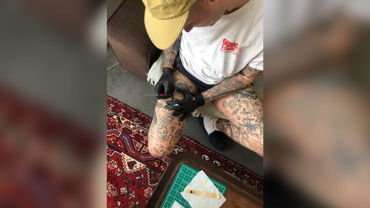Chris Woodhead tattooing himself.