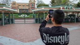 A man takes a photo outside the gates of Disneyland Park on the first day of the closure of Disneyland and Disney California Adventure theme parks as fear of the spread of coronavirus continue, in Anaheim, California, on March 14, 2020. - The World Health Organization said March 13, 2020 it was not yet possible to say when the COVID-19 pandemic, which has killed more than 5,000 people worldwide, will peak. "It's impossible for us to say when this will peak globally," Maria Van Kerkhove, who heads the WHO's emerging diseases unit, told a virtual press conference, adding that "we hope that it is sooner rather than later". (Photo by David McNew/AFP/Getty Images)