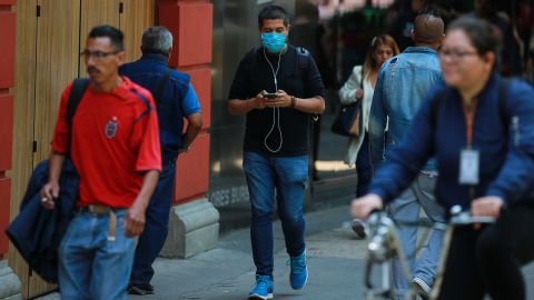 A man wearing a face mask walks with his phone on February 28, 2020 in Mexico City, Mexico.