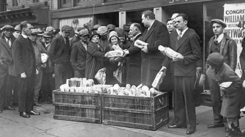 Reverend Raymond Brown and others hand out packages of food to the jobless outside St. Peter's Mission in New York City during the Depression.