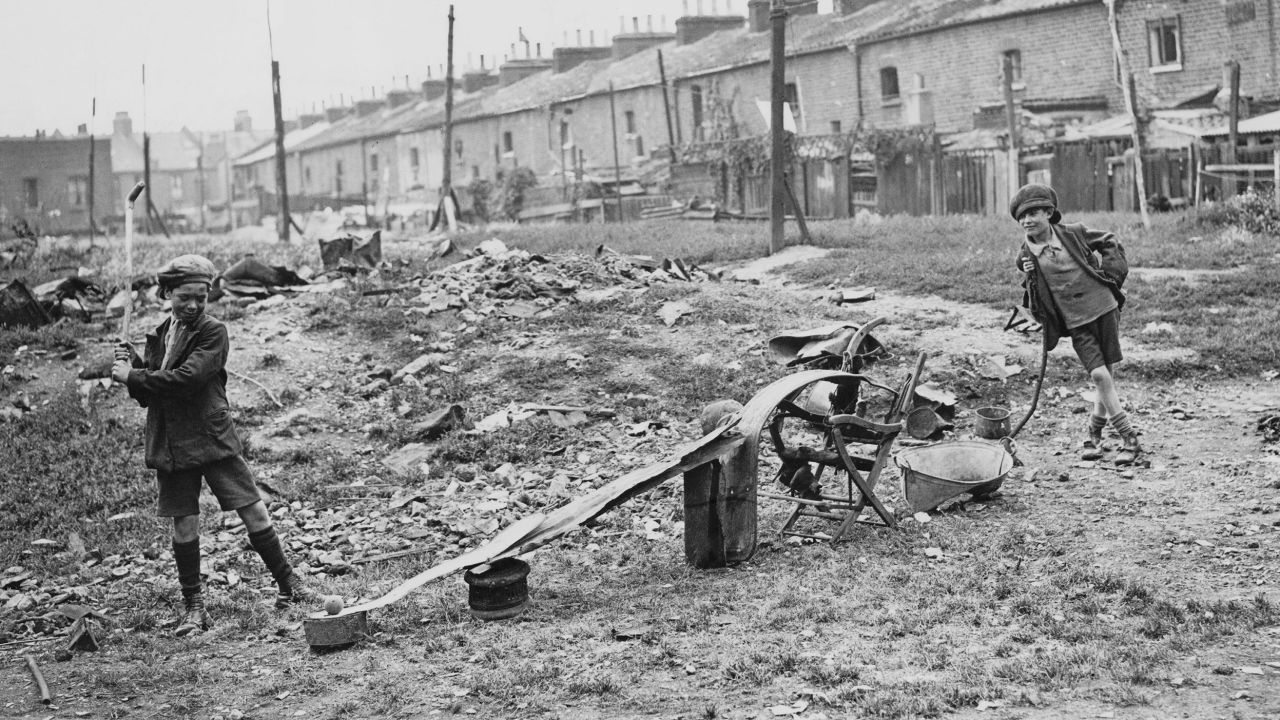 Two boys playing an improvised game of golf in an empty lot, 1930.