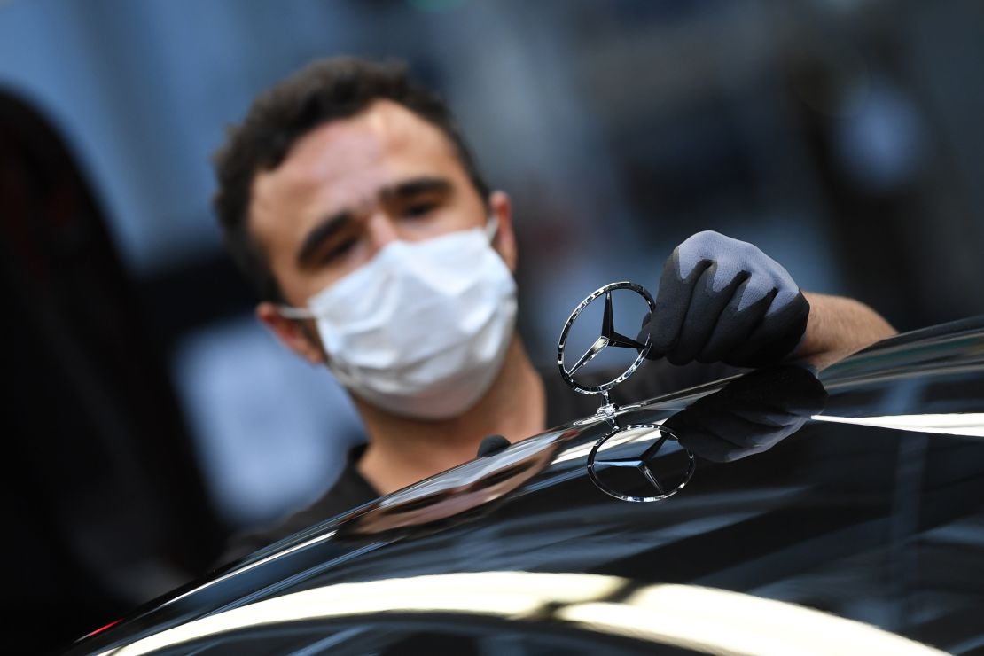 A worker adjusts the Mercedes logo on a car at a production line at the Mercedes-Benz plant in Sindelfingen, Germany, on April 30.