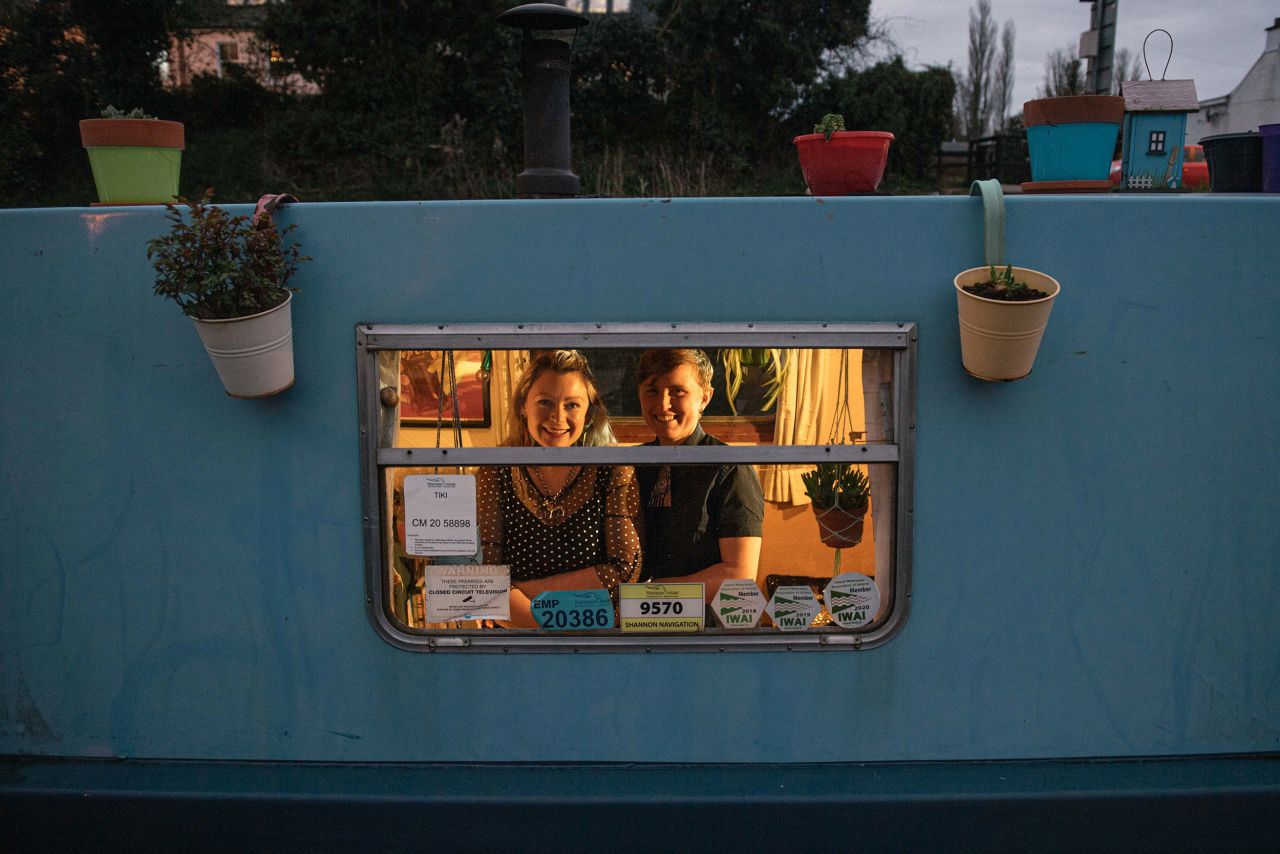 Claire and Ais are photographed through the window of their houseboat.