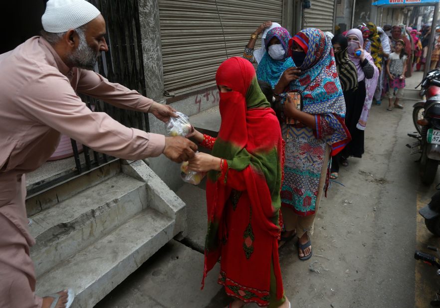 A man hands out food to women in Lahore, Pakistan, on May 6.