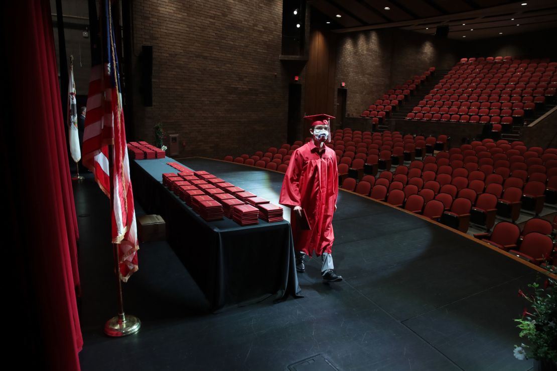 A student picks up his diploma during a graduation ceremony at Bradley-Bourbonnais Community High School in Bradley, Illinois. Because of social distancing mandates instituted by the state to curtail the spread of Covid-19, graduates received their diplomas in a nearly-empty auditorium with no friends, family or relatives allowed to attend. 