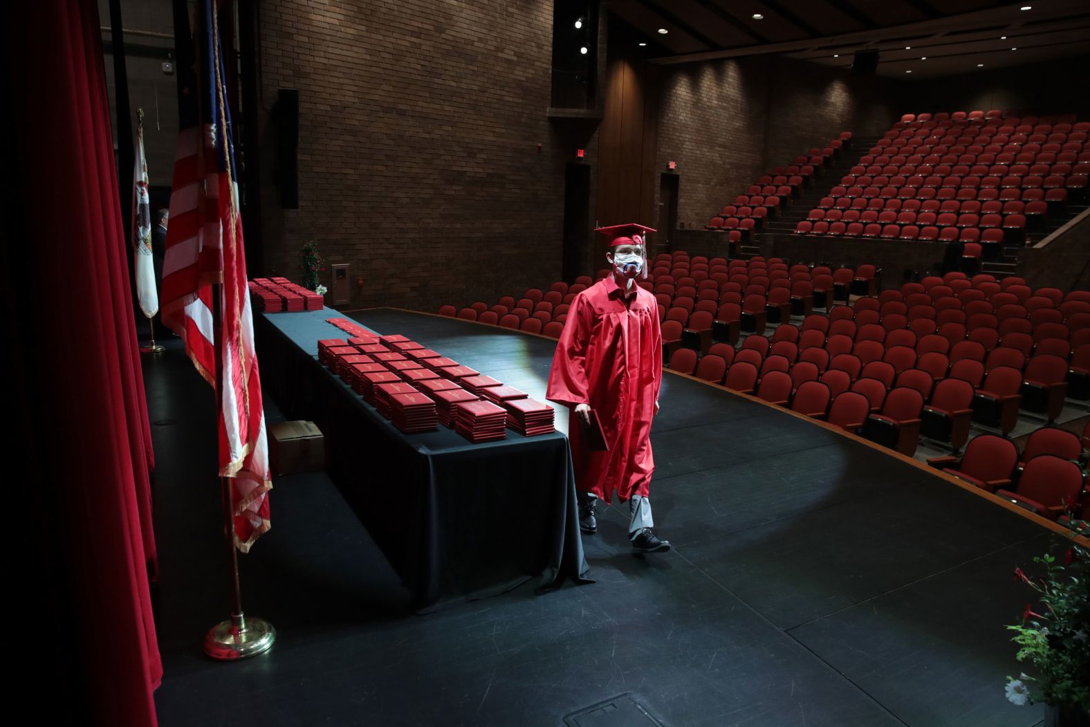 A student picks up his diploma May 6 during a graduation ceremony at Bradley-Bourbonnais Community High School in Bradley, Illinois. Because of social-distancing mandates instituted by the state, graduates received their diplomas in a nearly empty auditorium with no friends or family allowed to attend.