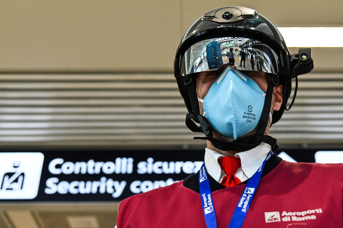 A Fiumicino airport employee displays a "Smart-Helmet" portable thermoscanner to screen passengers and staff for COVID-19, on May 5, 2020 at Rome's Fiumicino airport.