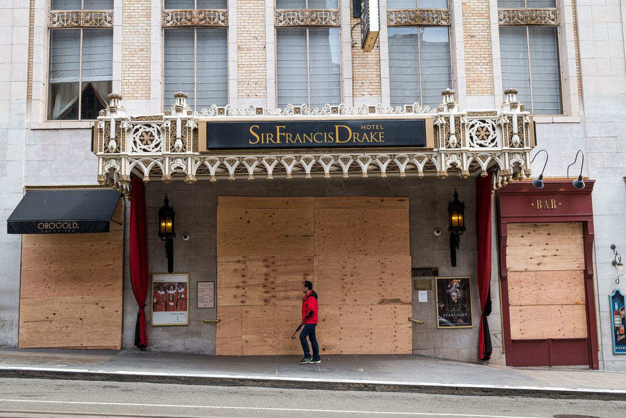 A pedestrian in San Francisco walks past a boarded-up St. Francis Drake Hotel on March 24. Governors from coast to coast told Americans not to leave home except for dire circumstances, and they ordered nonessential businesses to shut their doors. 