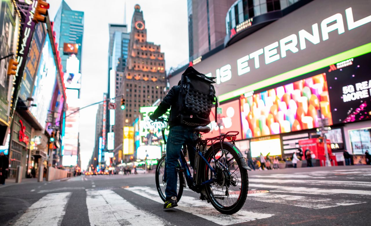 A food delivery worker crosses the street in New York's Times Square on March 17. Food delivery workers have become essential in the city after restaurants and bars closed. 