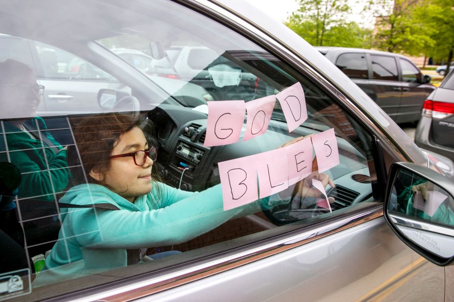 Elizabeth Ruiz, 7, puts up Post-It notes that spell out "God Bless U" as she and her mother, Daylin Lemus, wait in a line of hundreds of cars at a food bank in Hyattsville, Maryland, on May 5. "This is the first food bank we have come to," Lemus said. "My income is less than before, so we are coming in case things get worse. I'm worried about stores running out of chicken. I have been looking for two weeks and can't find it anywhere." 