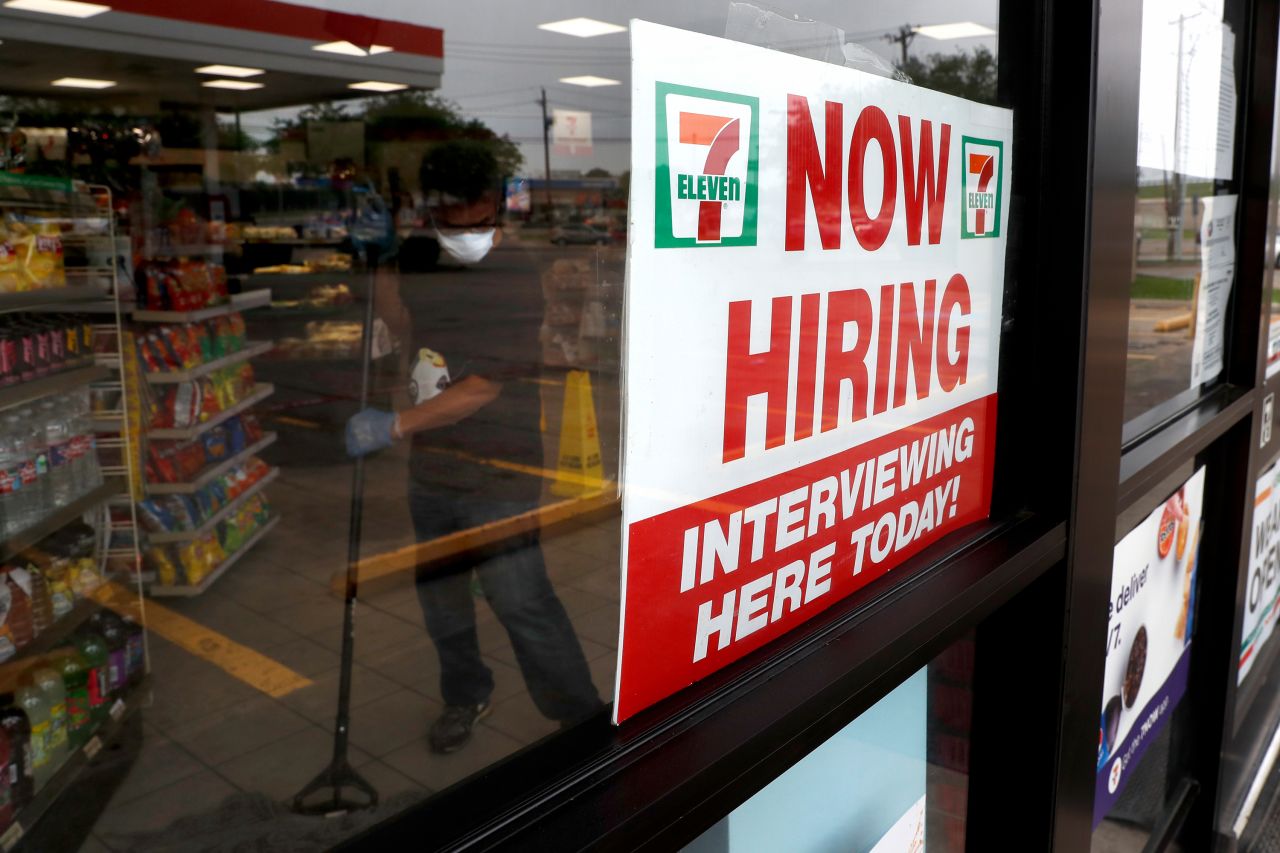 A sign at a 7-Eleven store in Dallas reads "Now Hiring" as an employee inside the store mops the floor in April.