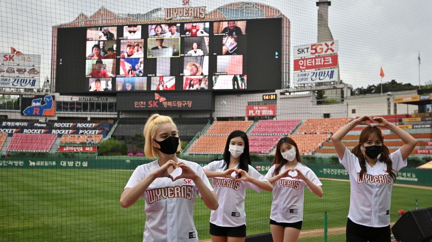 Cheerleaders pose in front of a big screen displaying baseball fans cheering from their homes during the opening game of South Korea's new baseball season between the SK Wyverns and Hanwha Eagles at Munhak Baseball Stadium in Incheon on May 5, 2020. - South Korea's professional sport returned to action on May 5 after the coronavirus shutdown with the opening of a new baseball season, while football and golf will soon follow suit in a ray of hope for suspended competitions worldwide. (Photo by Jung Yeon-je / AFP) (Photo by JUNG YEON-JE/AFP via Getty Images)