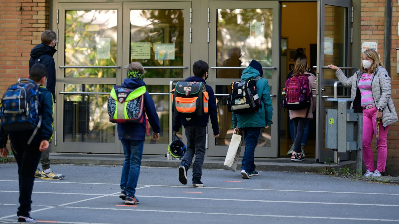 Children respect social distancing rules as they enter the Petri primary school in Dortmund, western Germany, on Thursday, as the school reopens for some pupils.