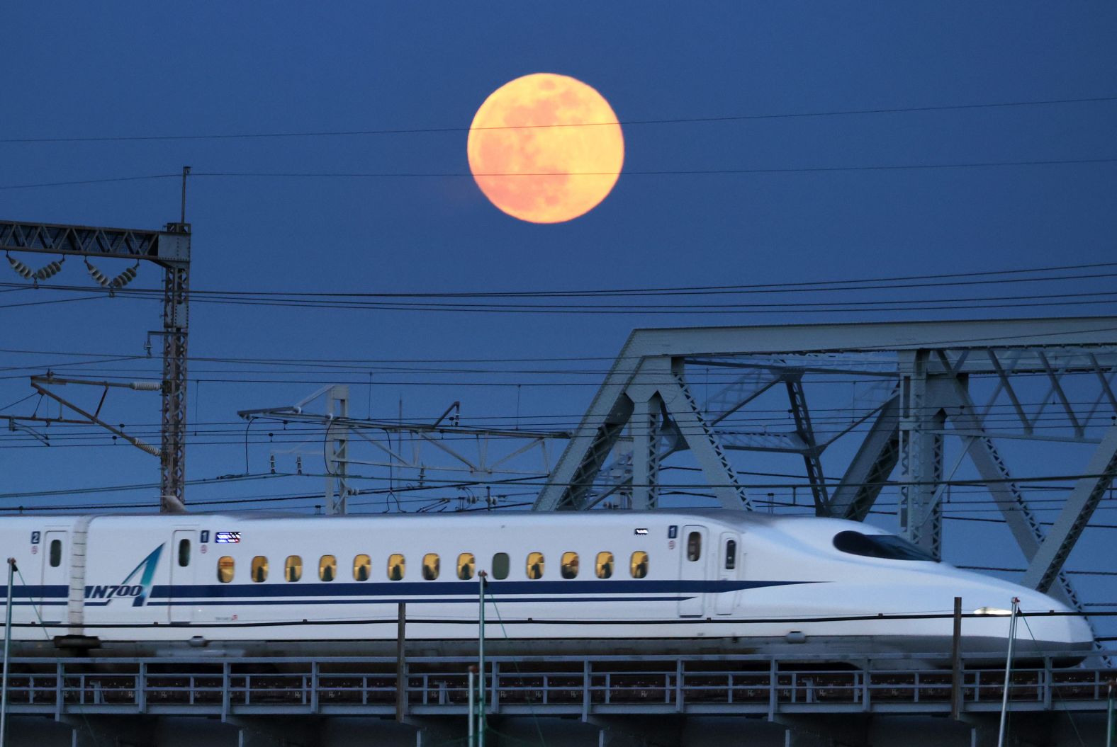 The moon appears above a bullet train in Tokyo.