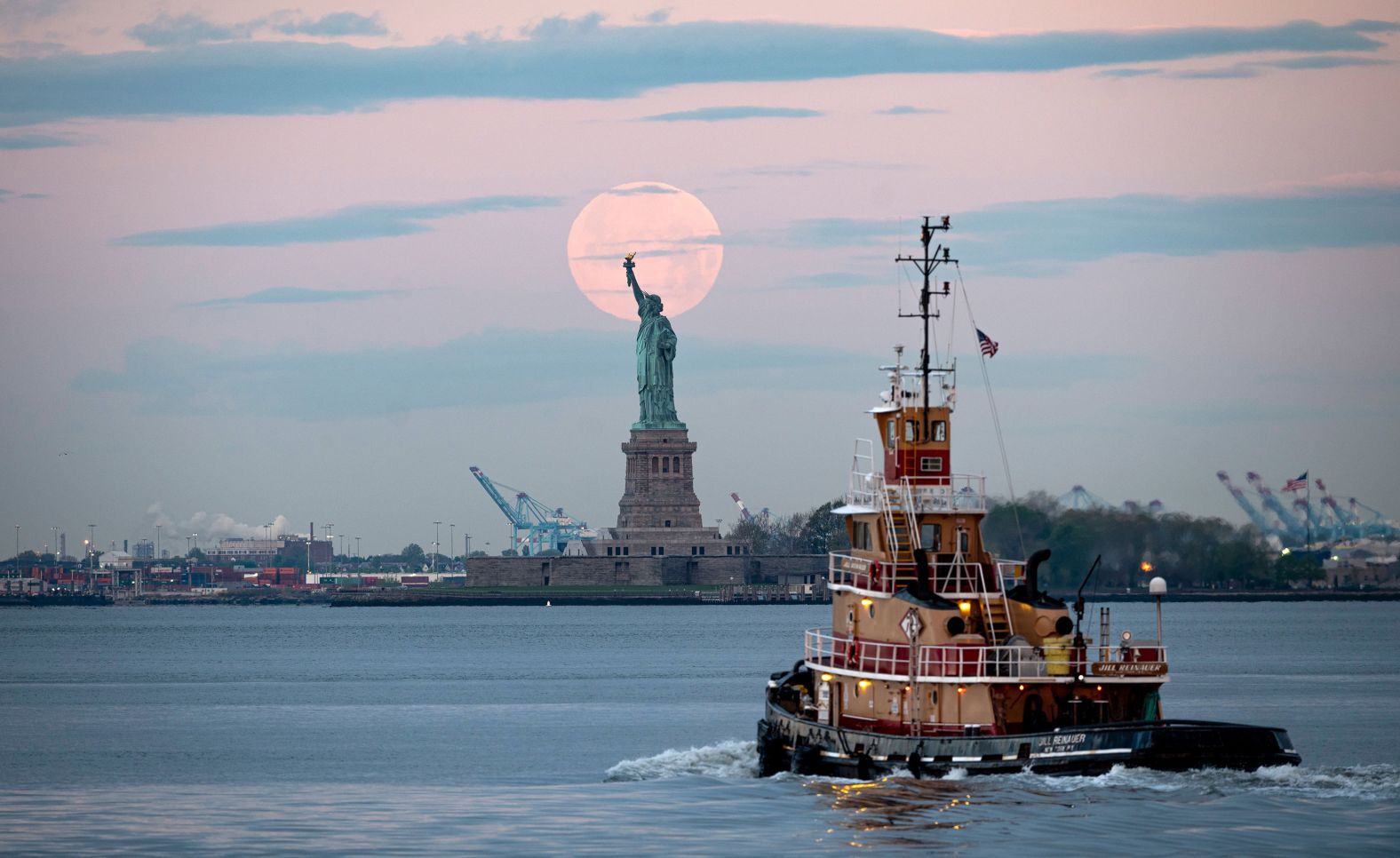 The moon is seen behind the Statue of Liberty in New York.