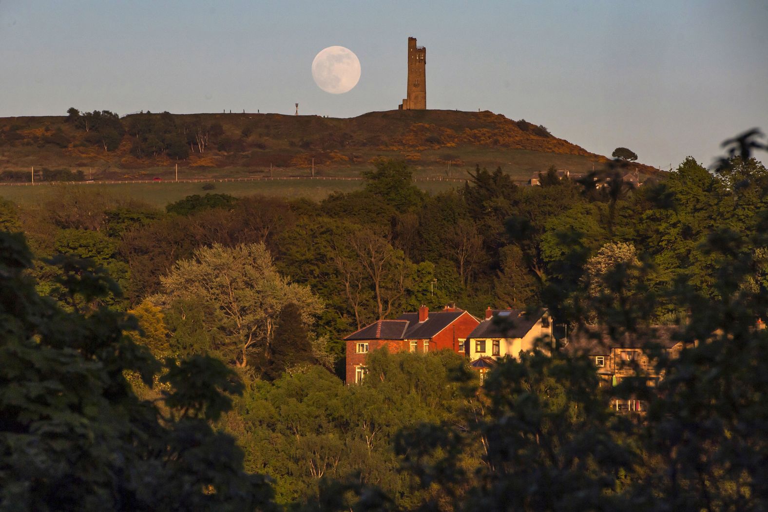 The moon rises behind Victoria Tower in Huddersfield, England.