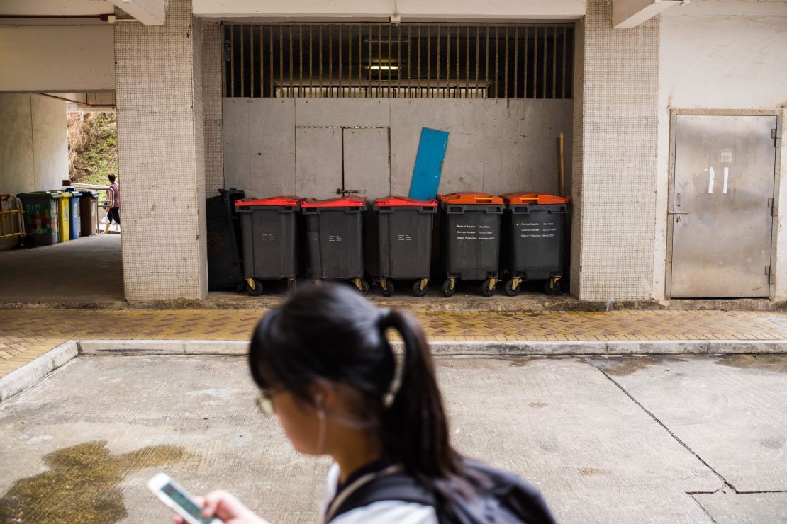A girl walks past large trash bins at housing estate where the 2018 rat hepatitis patient lived. A rat infestation was found in the estate.