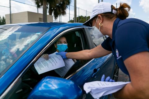 City employee Tatiana Fernandez distributes unemployment forms outside the John F. Kennedy Library in Hialeah, Florida, on April 7.