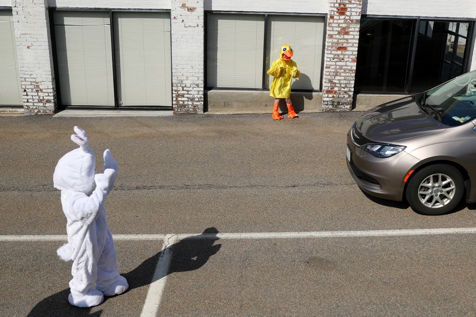Landon Phillips, dressed as the Easter Bunny, and Boston Phillips, dressed as a chick, wave to cars in Newton, Massachusetts, during a drive-thru photo session at StoryHeights Church on April 11.