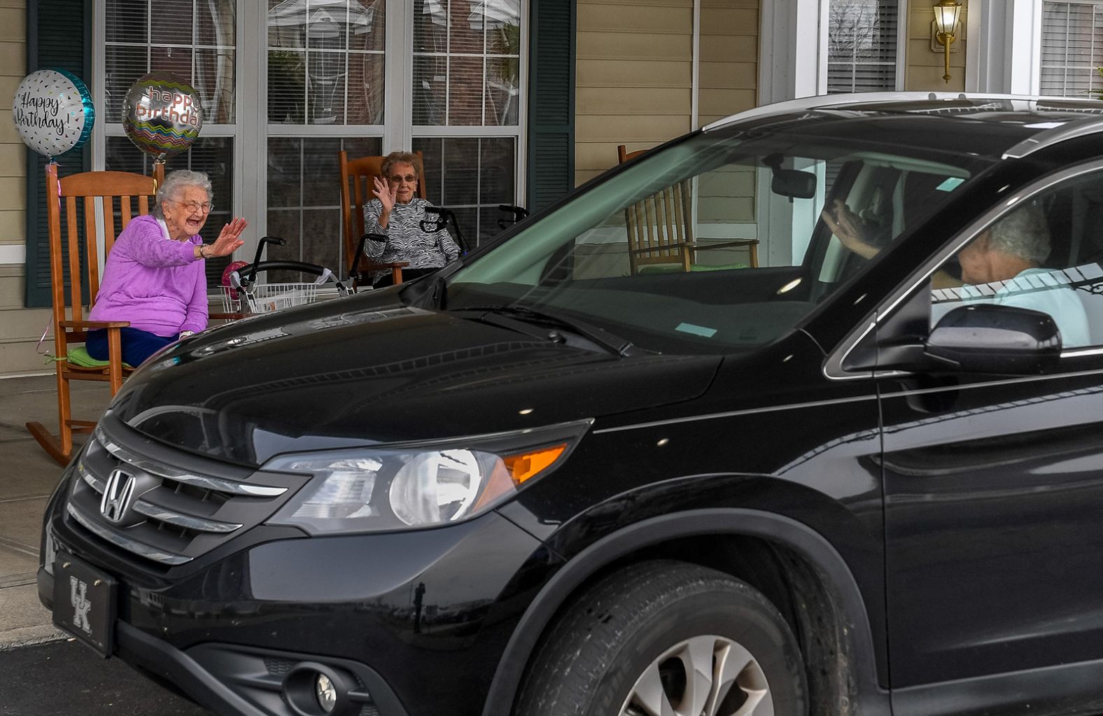 Pauline Thompson, left, waves to a passing car during <a href="index.php?page=&url=https%3A%2F%2Fwww.thegleaner.com%2Fstory%2Fnews%2F2020%2F03%2F31%2Fnursing-homes-go-extra-mile-keep-residents-linked-during-covid-19%2F2918091001%2F" target="_blank" target="_blank">her drive-thru birthday party</a> in Henderson, Kentucky, on March 27. Thompson, a resident at the Colonial Assisted Living facility, was turning 97, and she had a drive-thru party because she was unable to celebrate with family and friends.