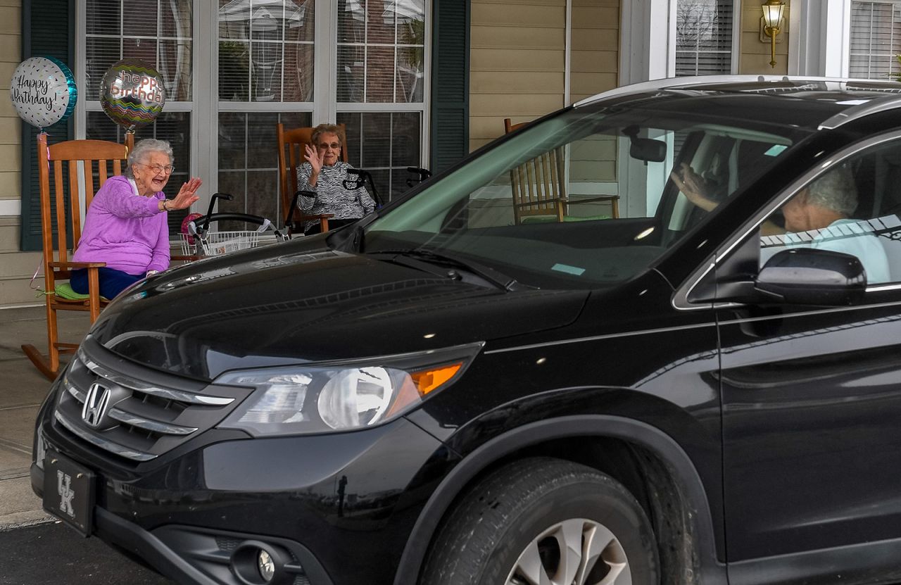 Pauline Thompson, left, waves to a passing car during <a href="https://www.thegleaner.com/story/news/2020/03/31/nursing-homes-go-extra-mile-keep-residents-linked-during-covid-19/2918091001/" target="_blank" target="_blank">her drive-thru birthday party</a> in Henderson, Kentucky, on March 27. Thompson, a resident at the Colonial Assisted Living facility, was turning 97, and she had a drive-thru party because she was unable to celebrate with family and friends.