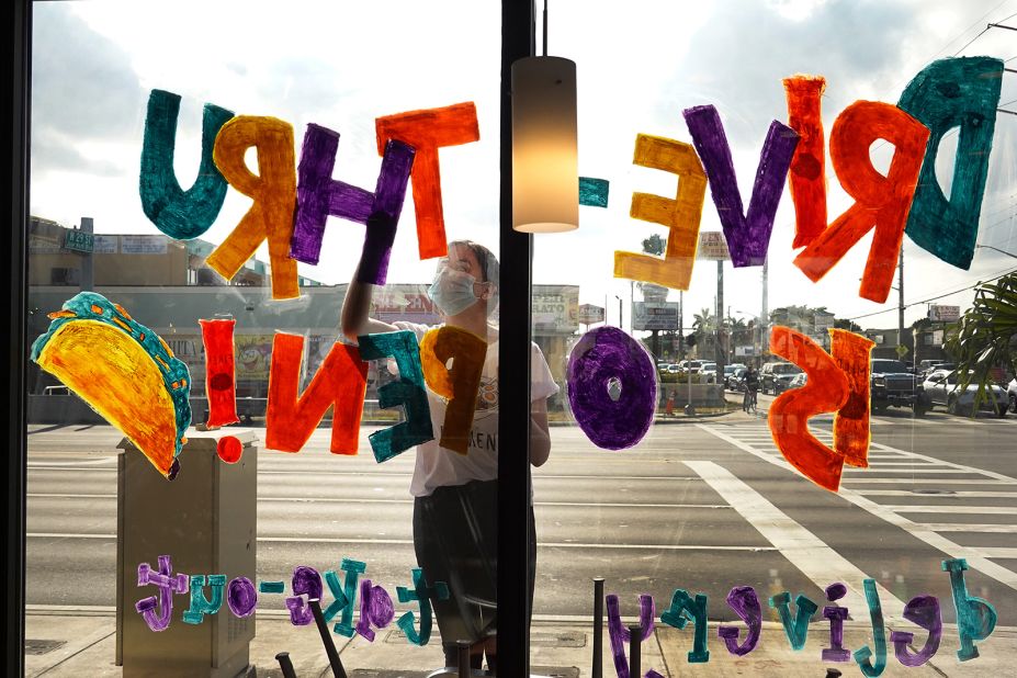 Amanda Gonzalez writes "drive-thru is open!" on the window of a Taco Bell restaurant in Miami on April 7.