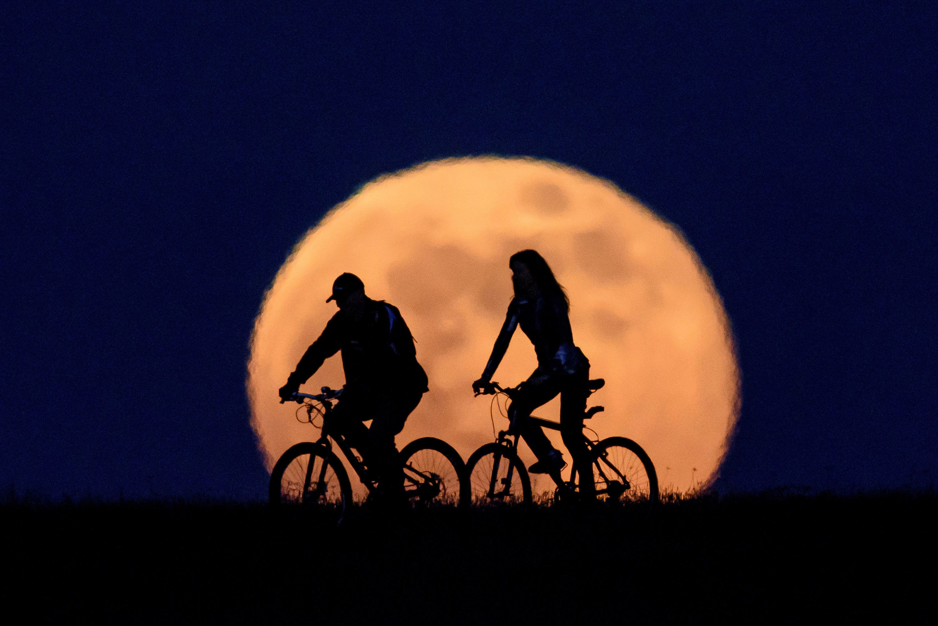 A full moon rises above two cyclists near Salgotarjan, Hungary, on Thursday, May 7.
