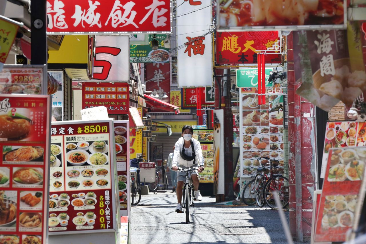 A man wearing a face mask cycles through Chinatown in Yokohama, Japan, on May 8, 2020. Prime Minister Shinzo Abe announced that Japan would extend its state of emergency until the end of May.