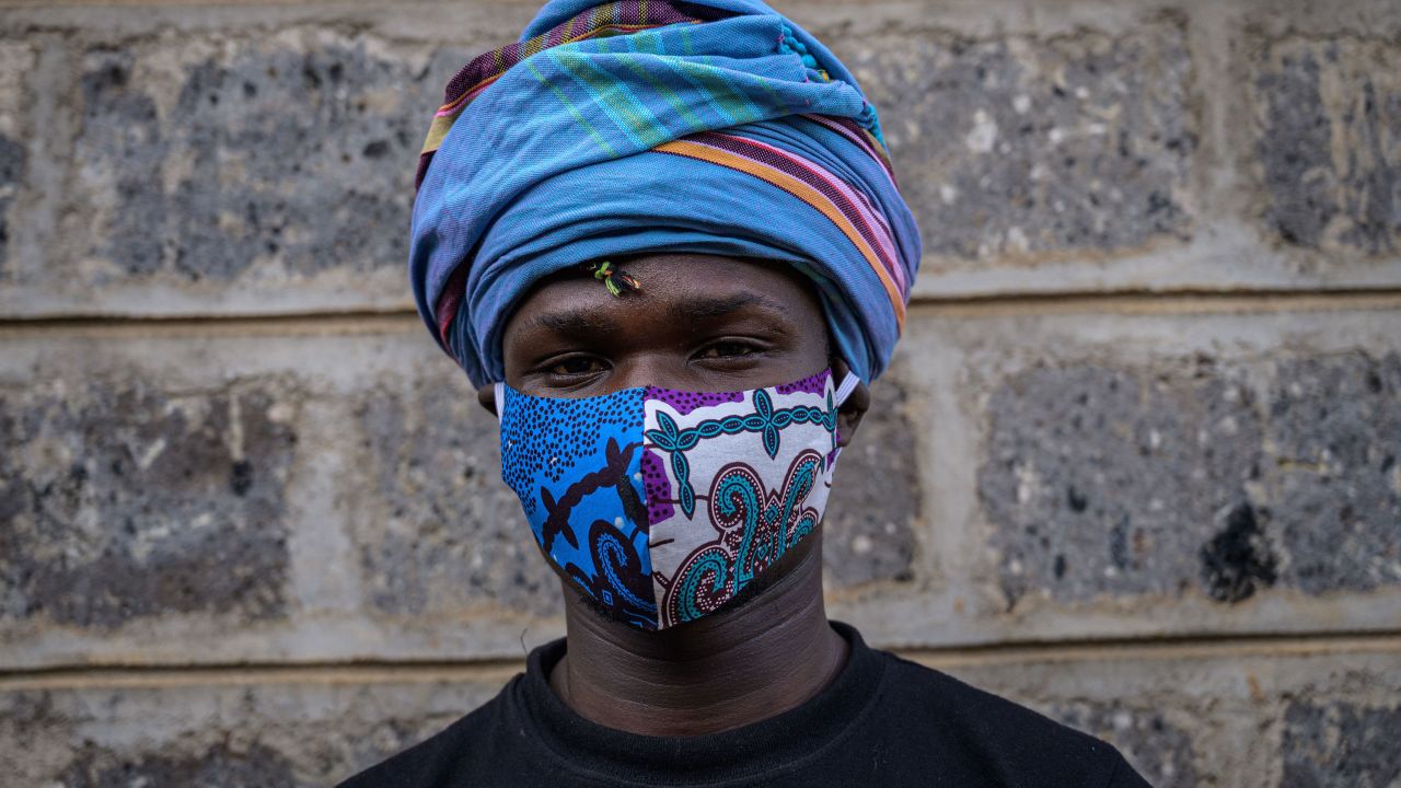 Kenyan fashion designer of "Lookslikeavido", David Avido, poses for a portrait at his studio in Kibera, Nairobi, with a mask he created to hand out to people for free. 