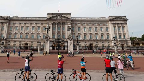 Cyclists watch as the Red Arrows fly over Buckingham Palace in London.