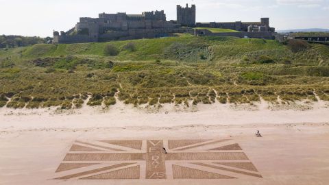 Andrew Heeley, a maintenance manager at Bamburgh Castle, draws a giant Union Jack flag on a beach in Northumberland, England.