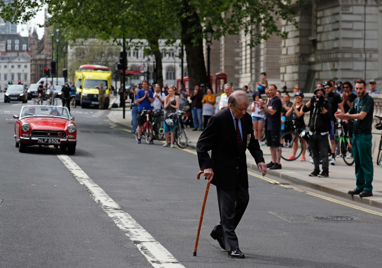 People applaud as a World War II veteran walks past them in London.