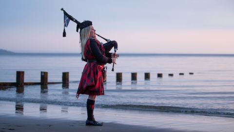 Louise Marshall plays the bagpipes at dawn along Portobello Beach in Edinburgh, Scotland.