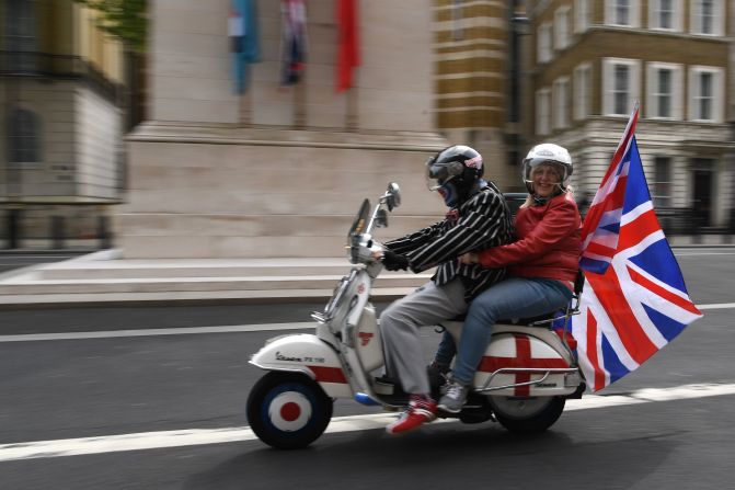 A couple carries a Union Jack flag as they drive past The Cenotaph war memorial in London.