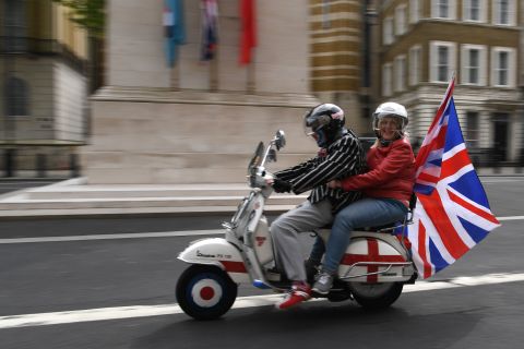 A couple carries a Union Jack flag as they drive past The Cenotaph war memorial in London.